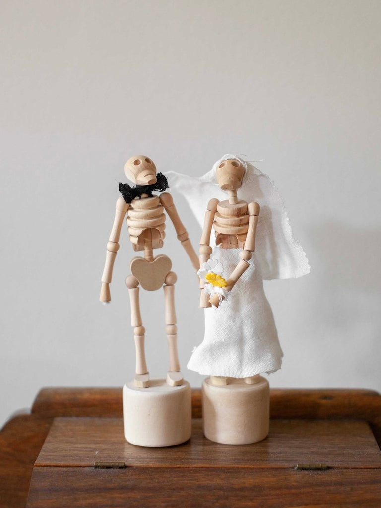 Two small movable wooden skeleton figures in wedding clothes getting married. 