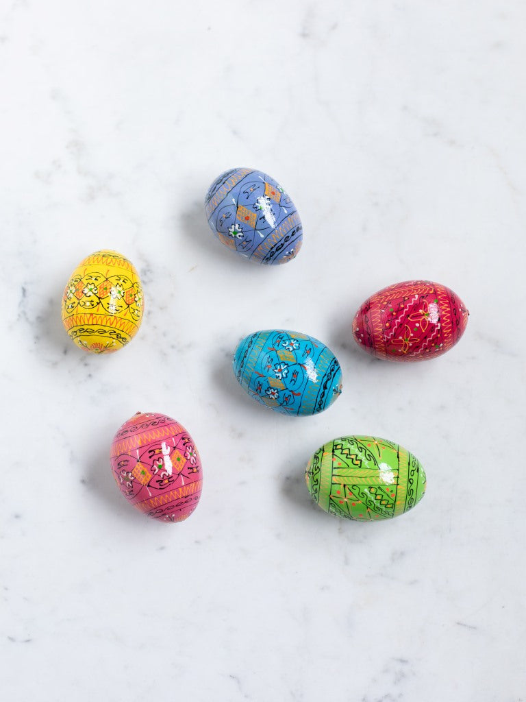 Six painted eggs in different colors laid out next to each other.
