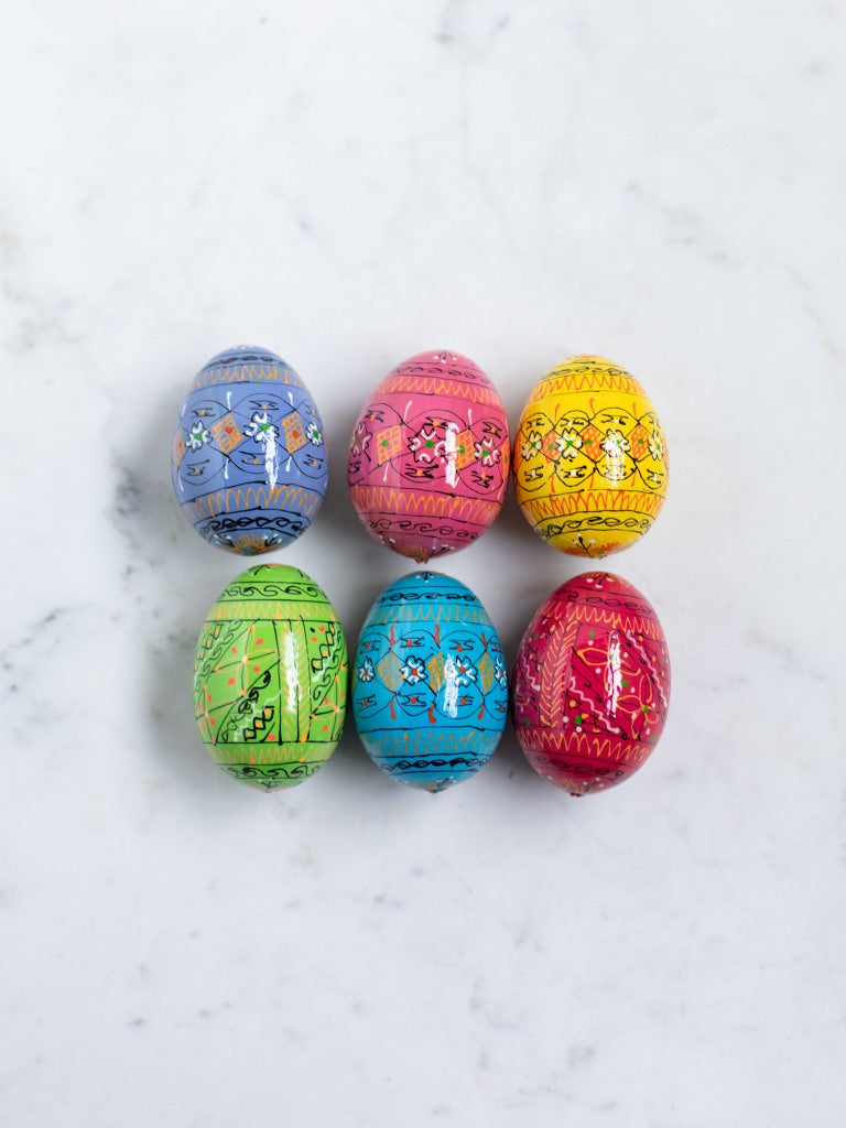 Six painted eggs in different colors laid out next to each other.