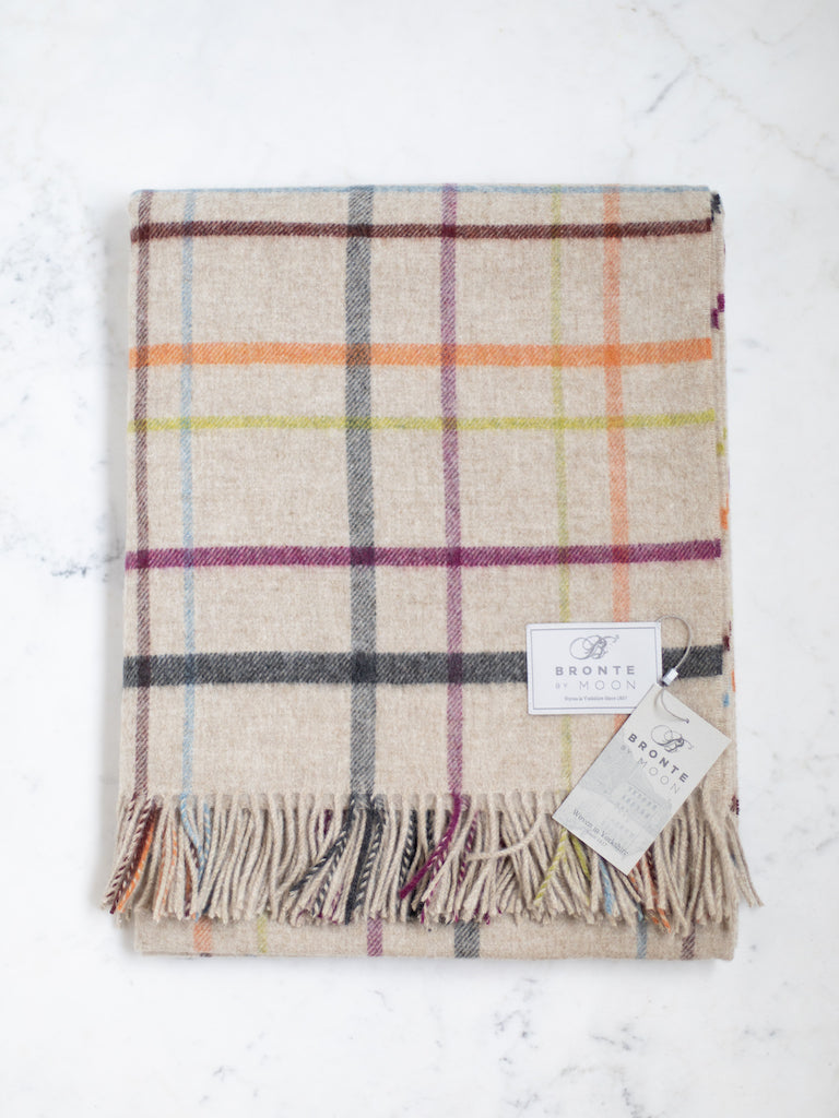 Merino Lambswool throw, a light grey base color with a purple, orange, green and blue small plaid pattern.