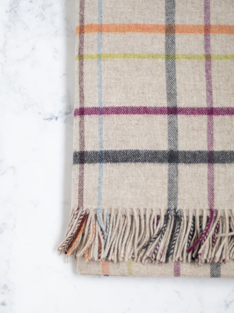 Merino Lambswool throw, a light grey base color with a purple, orange, green and blue small plaid pattern.