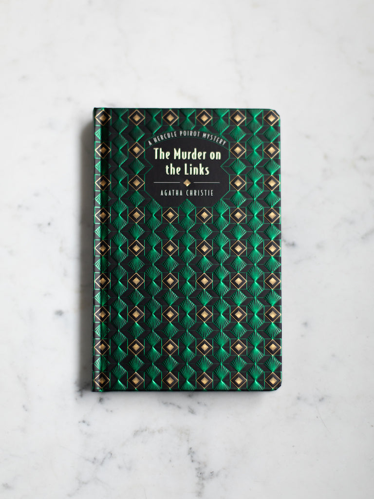 A deep green geometric patterned cover of “The Murder on the Links”