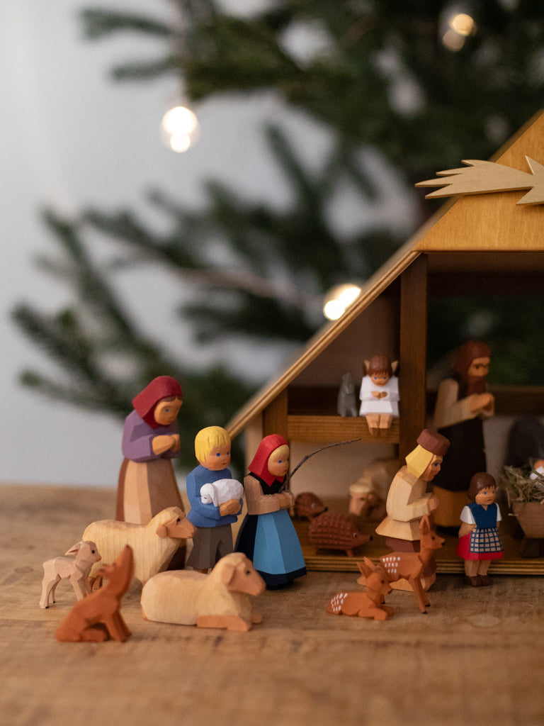 A focus of figurines of a woman with her two small children bowing to baby Jesus, surrounded by multiple sitting animals.