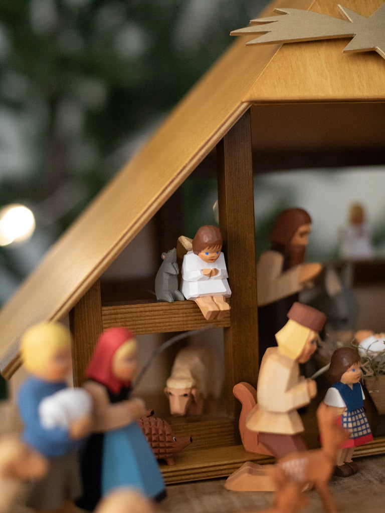 A nativity scene focused on a small sitting angel figurine with a rat figurine.