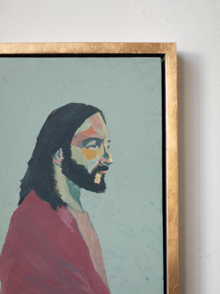 Up close photo of the light color blocking in the face of Jesus in a painting with a gold frame. 