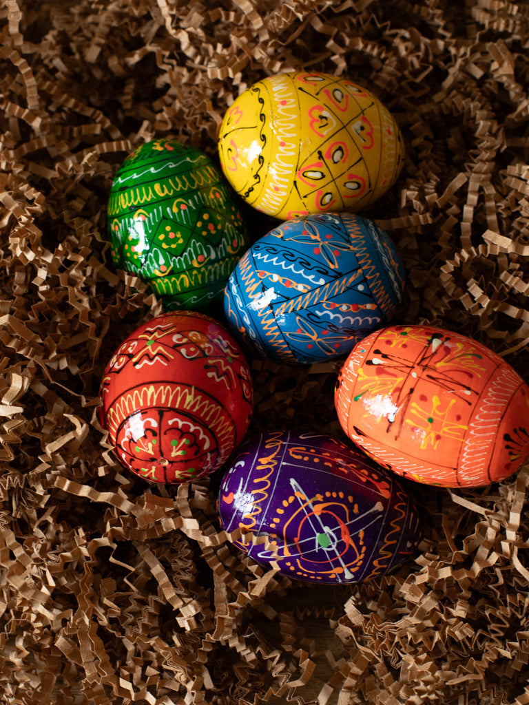 Six painted eggs in different colors laid out next to each other.