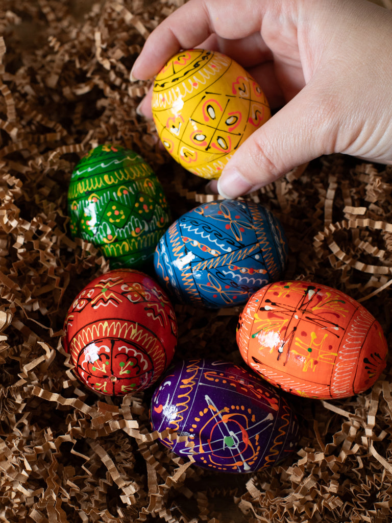 Six painted eggs in different colors laid out next to each other.