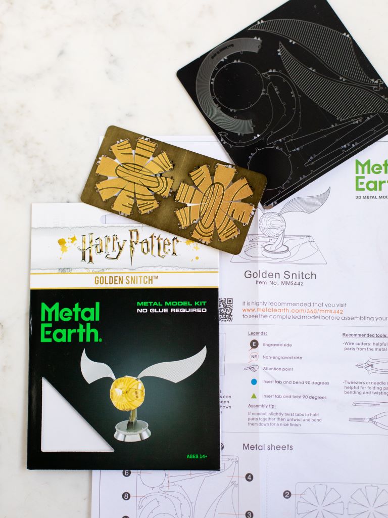 The instructions, pieces, and packaging cover of the golden snitch metal model.