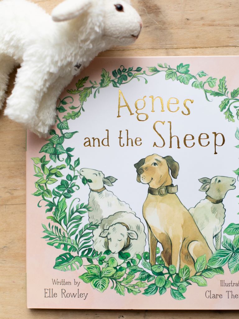 Close up of “Agnes and the Sheep” with a white sheep plushie laying nearby.
