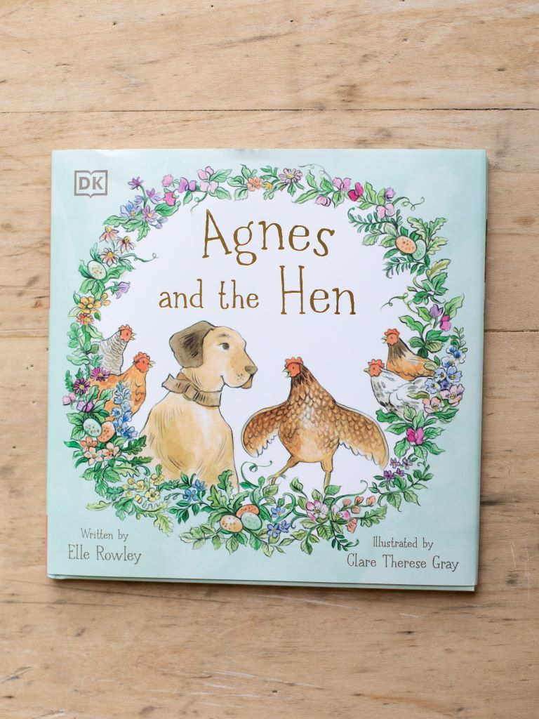 Front view of the pastel green cover of “Agnes and the Hen”. Agnes, a dog, is sitting alongside a hen in the middle of a dark green wreath.