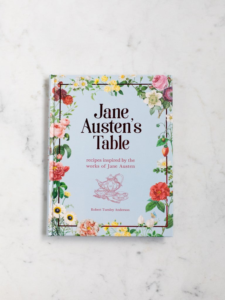 A blue cookbook covered in flowers titled “Jane Austen’s Table” with a tea set below the title. 