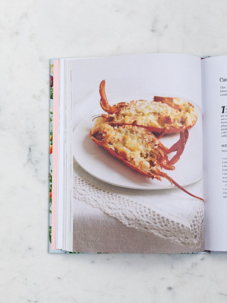 A cookbook opened to a photo of a seafood dish. 