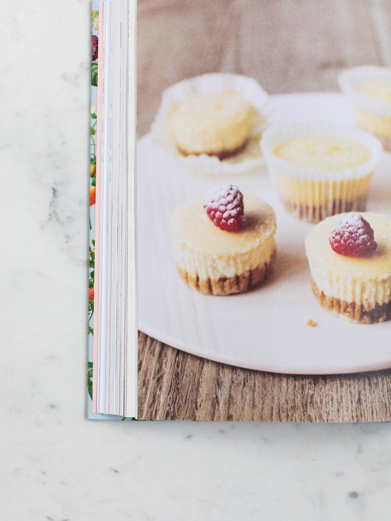A cookbook opened to a photo of a desert with raspberries. 
