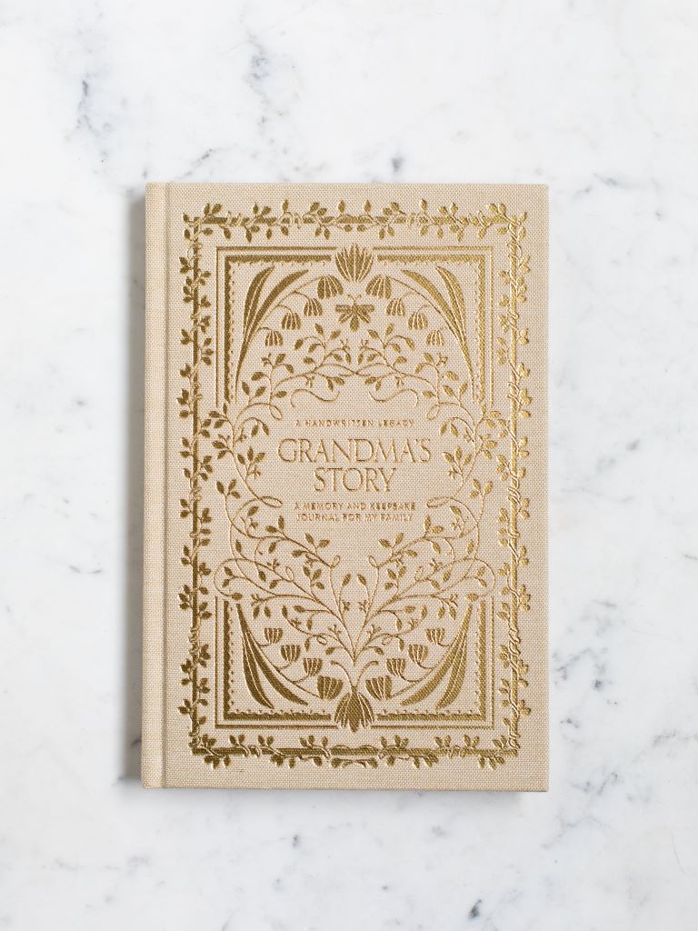 A cream clothbound book with gold designs of flowers and plants around the title “Grandma’s Story.”