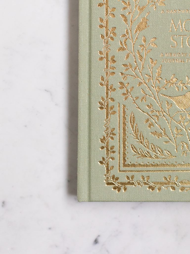 A close up photo of the gold designs of plants on a green clothbound book. 