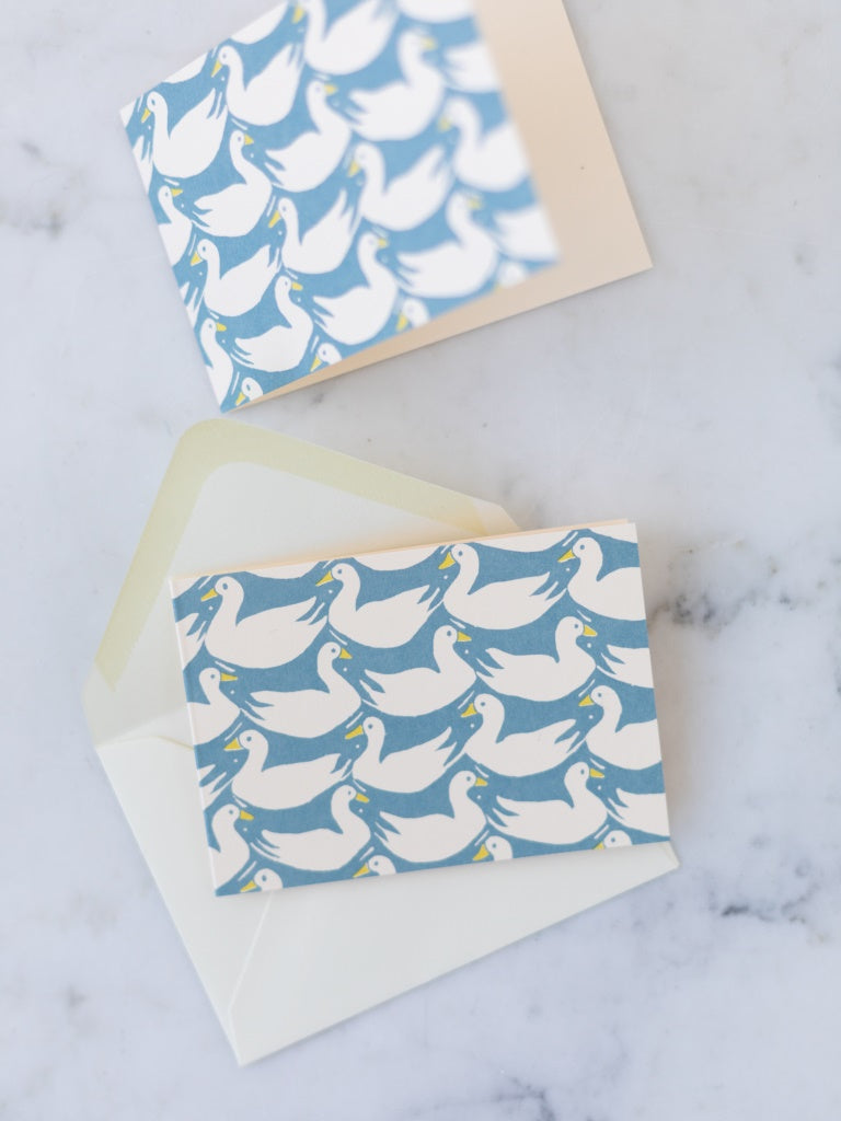 Ambitious image of white ducks and blue rabbits together on a mini card with an envelope behind it. 