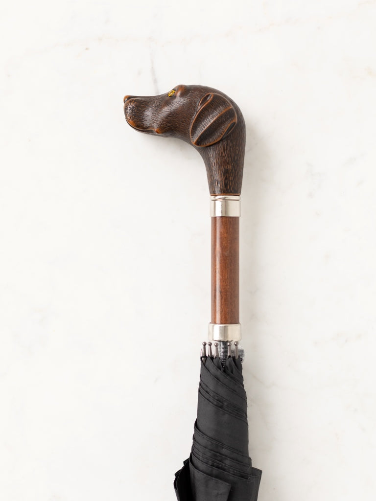 A umbrella handle in a club shape, as the end this the head of an attentive looking dog.