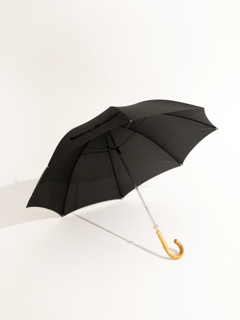 An opened black umbrella with a curved oak handle.
