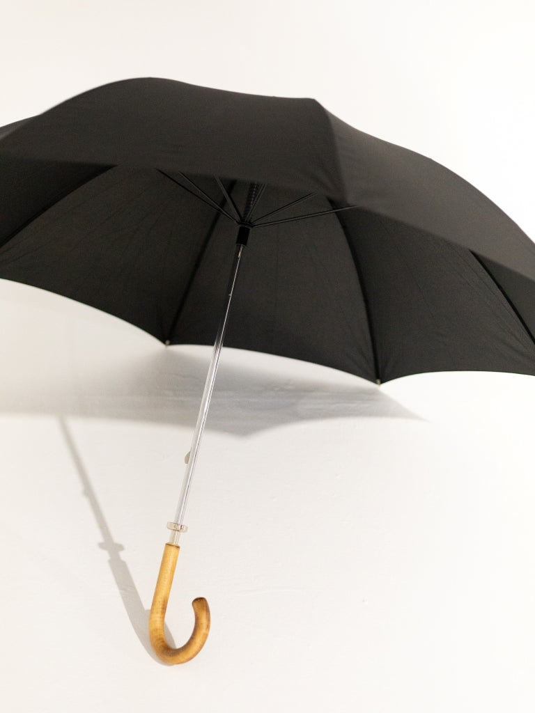 An opened black umbrella with a curved oak handle.