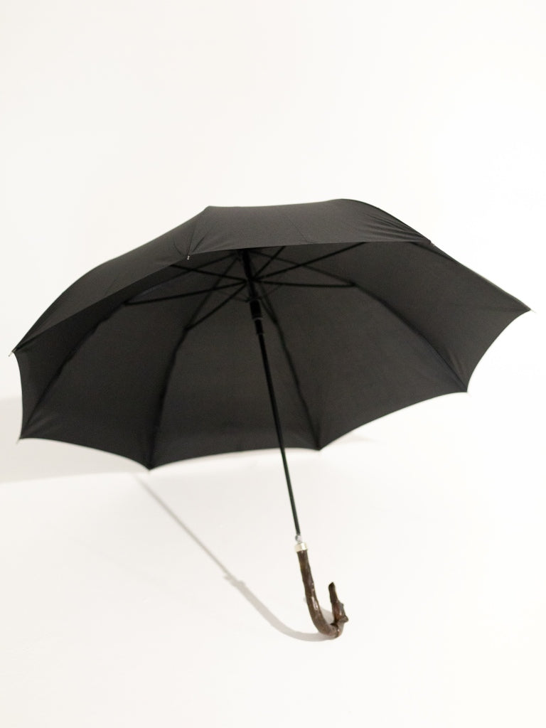 An opened black umbrella with a curved dark wood dog head handle.