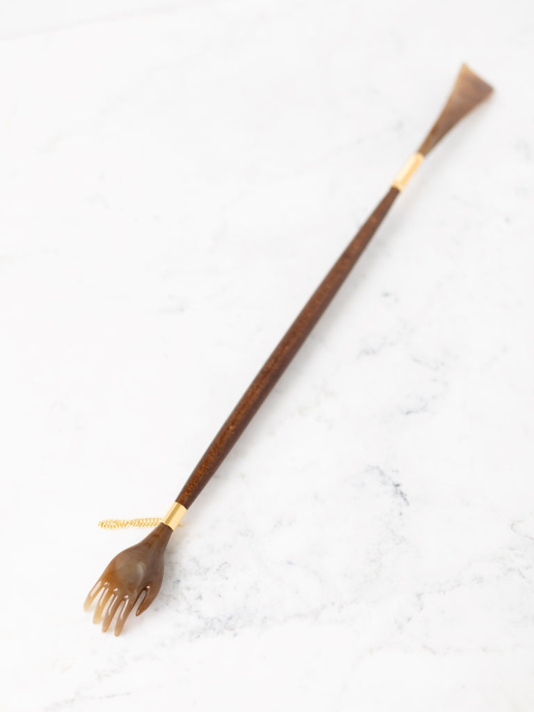 Full view of the back scratcher & shoe horn. One side of it is a hand, the other side is a horn. It has a gold chain attached to it.