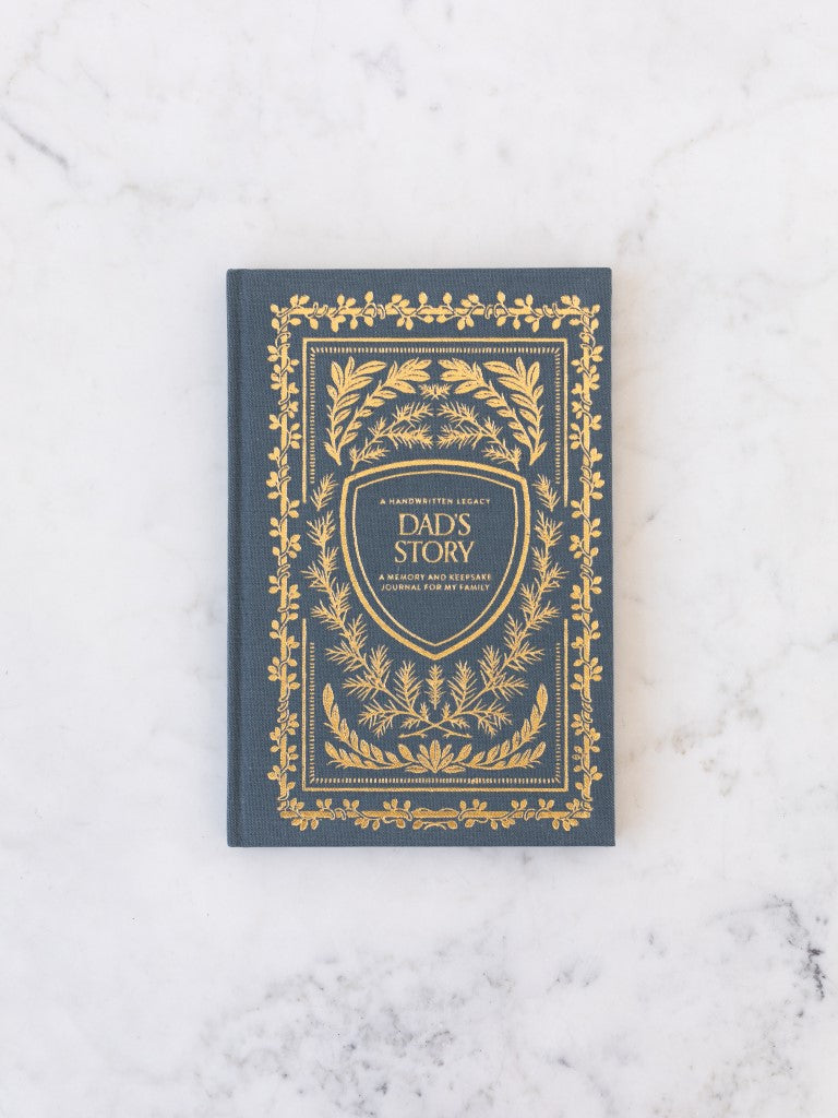 A blue clothbound book with gold designs of plants around the title “Dad’s Story.” 