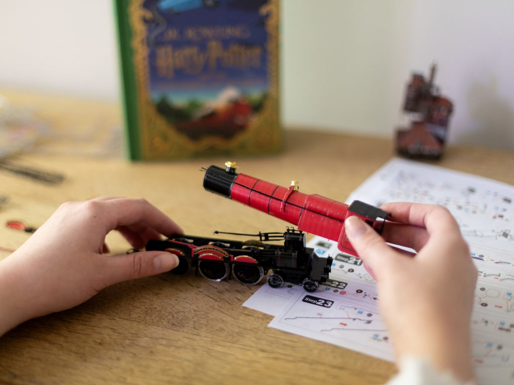 Two hands holding the pieces of the train mode, next to the list of building instructions.