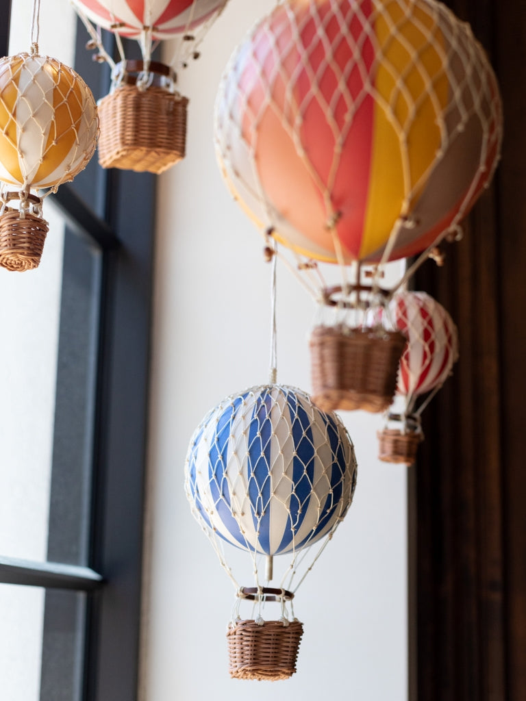 Various colored hot air balloons hanging in a window.