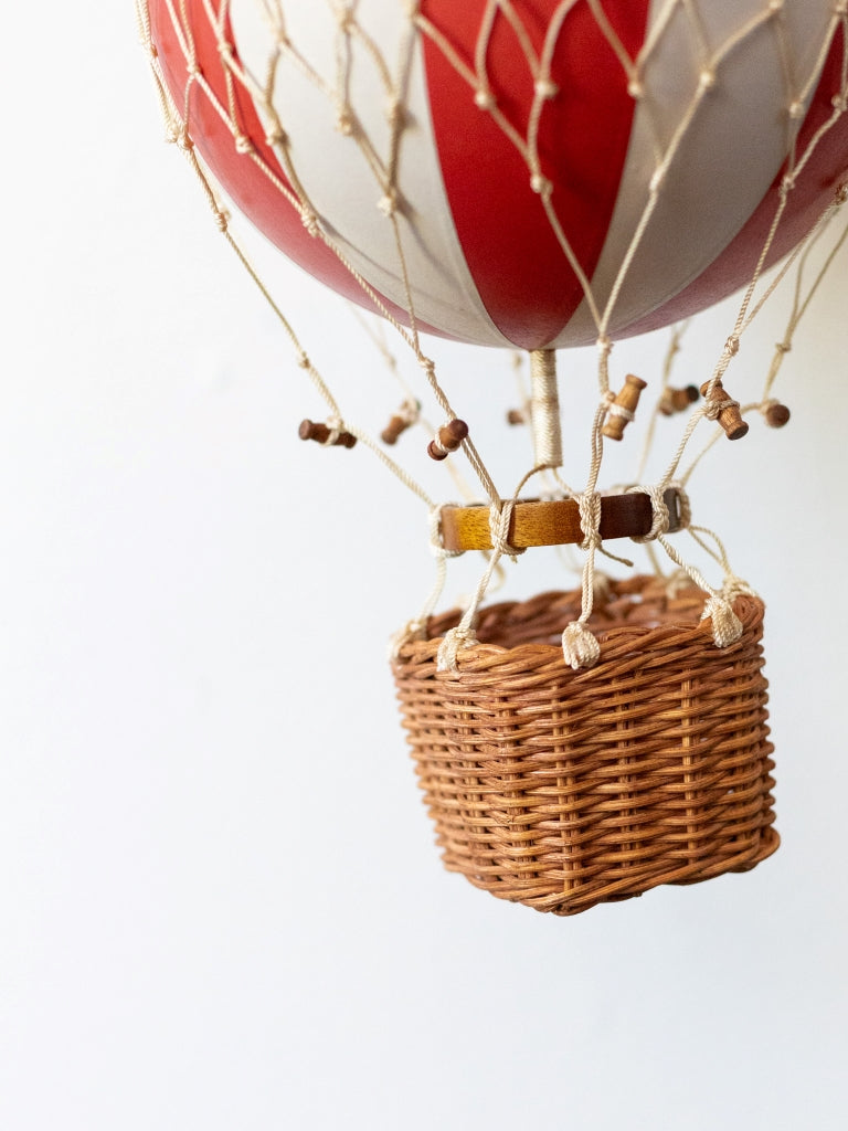 Large red and white striped balloon, covered in net with a small, woven basket connected to the bottom.