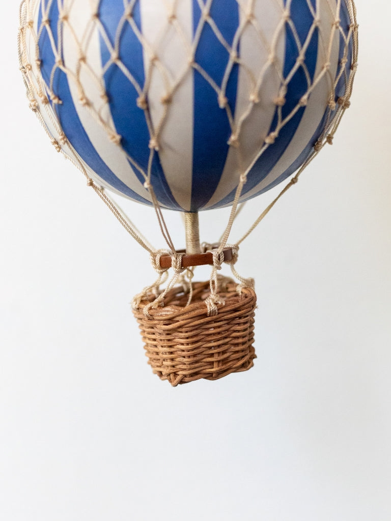 Medium blue and white striped balloon, covered in net with a small, woven basket connected to the bottom.