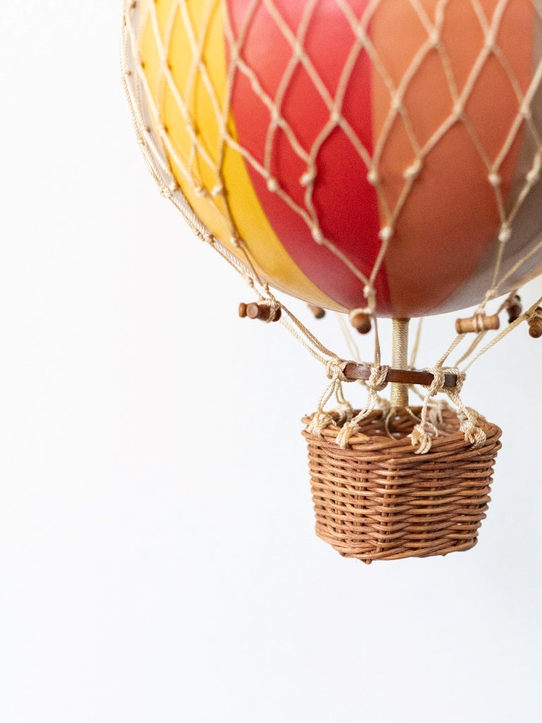 Large multicolored balloon, covered in net with a small, woven basket connected to the bottom.