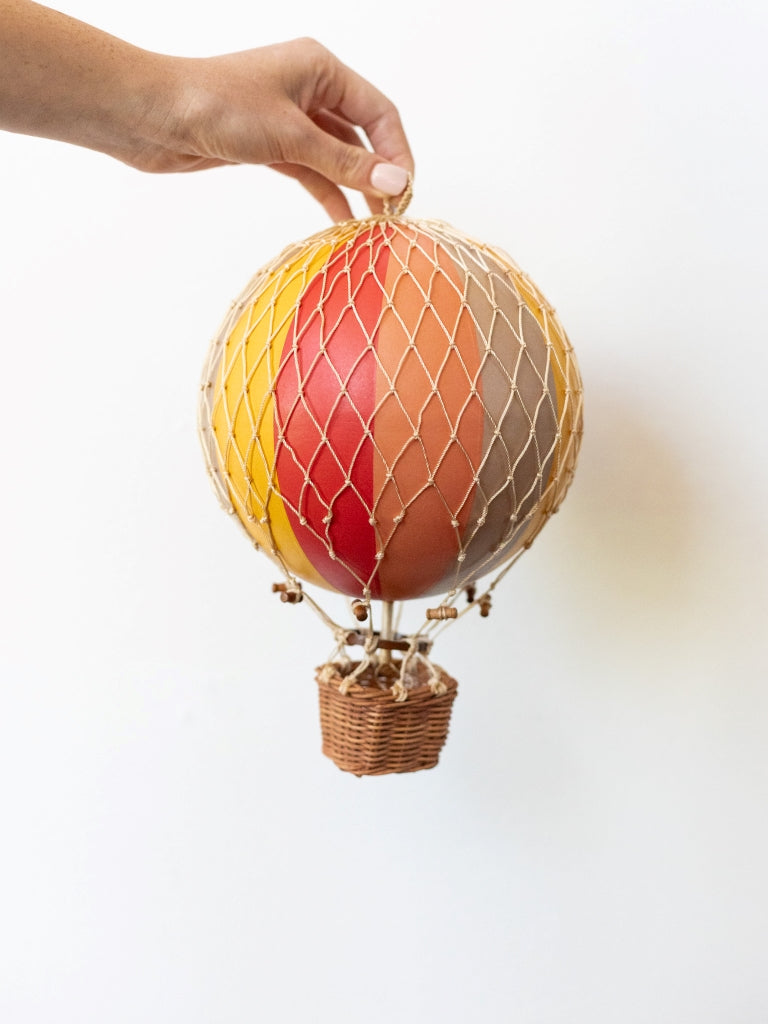 Large multicolored balloon, covered in net with a small, woven basket connected to the bottom.