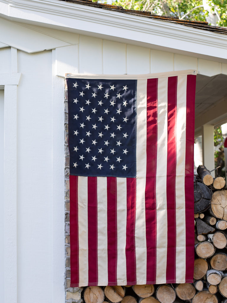 Long view of the Americana flag hanging down from a shed of logs.