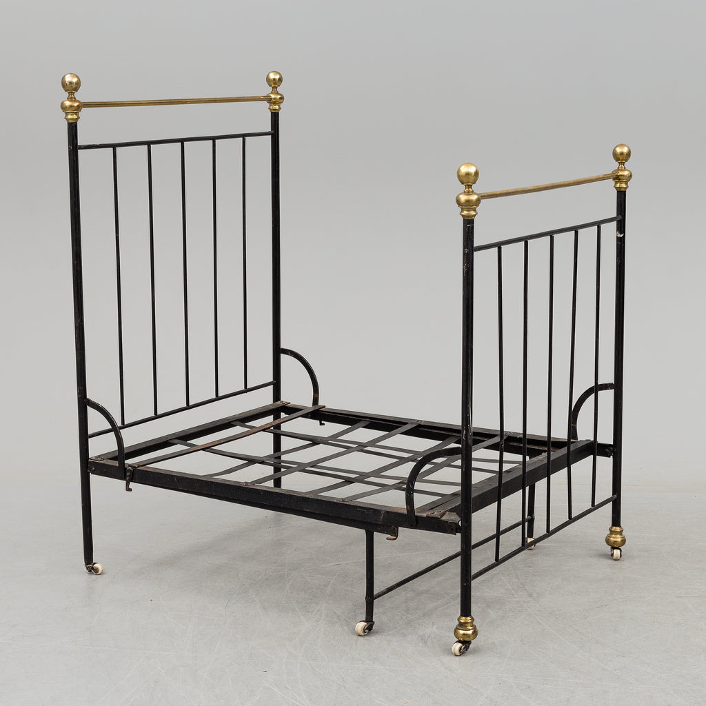 Black iron bed frame with brass bedknobs in the compact state