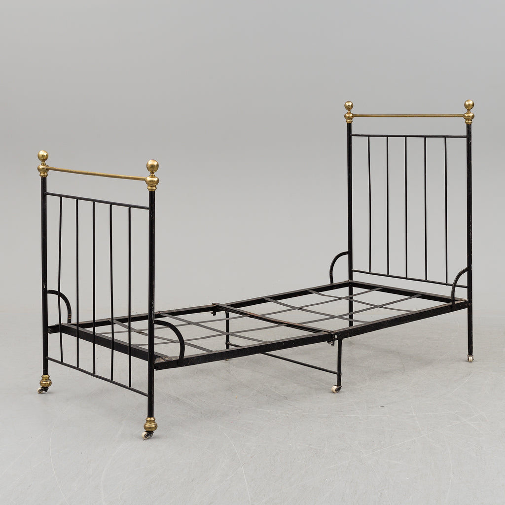 Black iron bed frame with brass bedknobs.