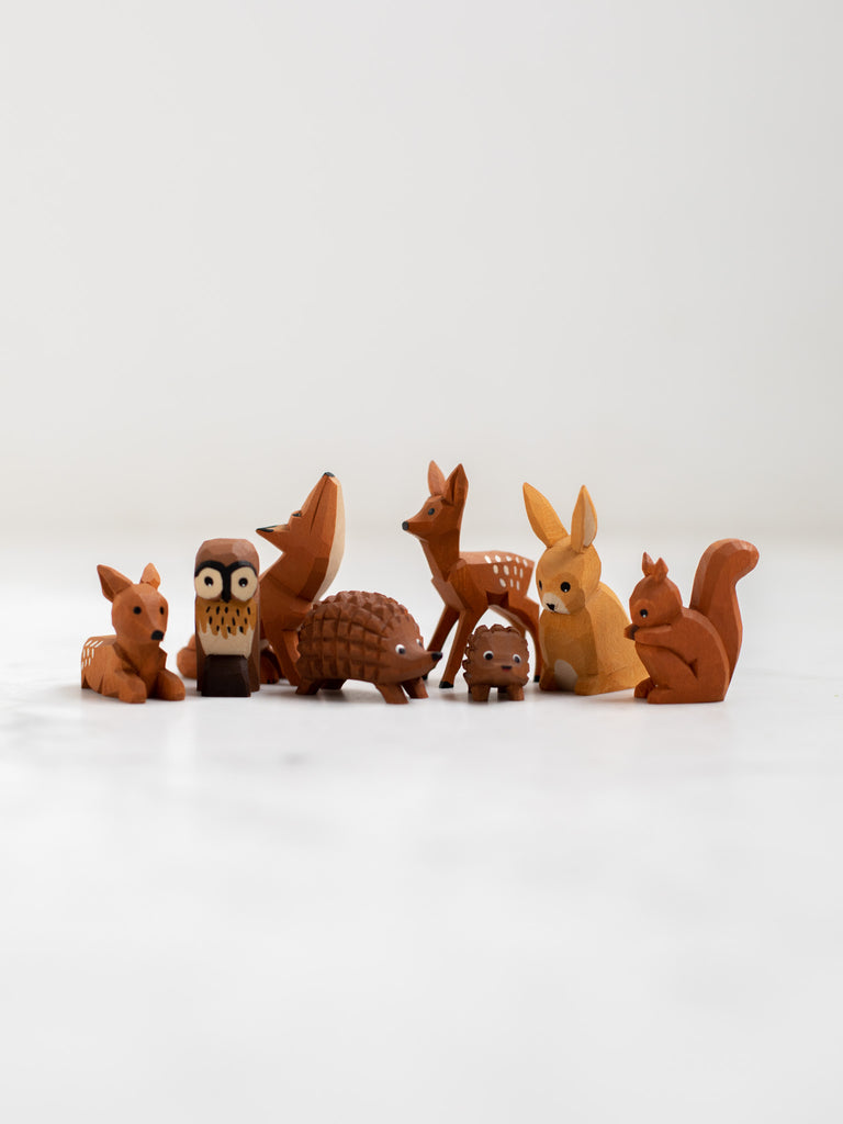 A collection of small woodland animal figurines including deer, rabbits, owls, squirrels, and hedgehogs.