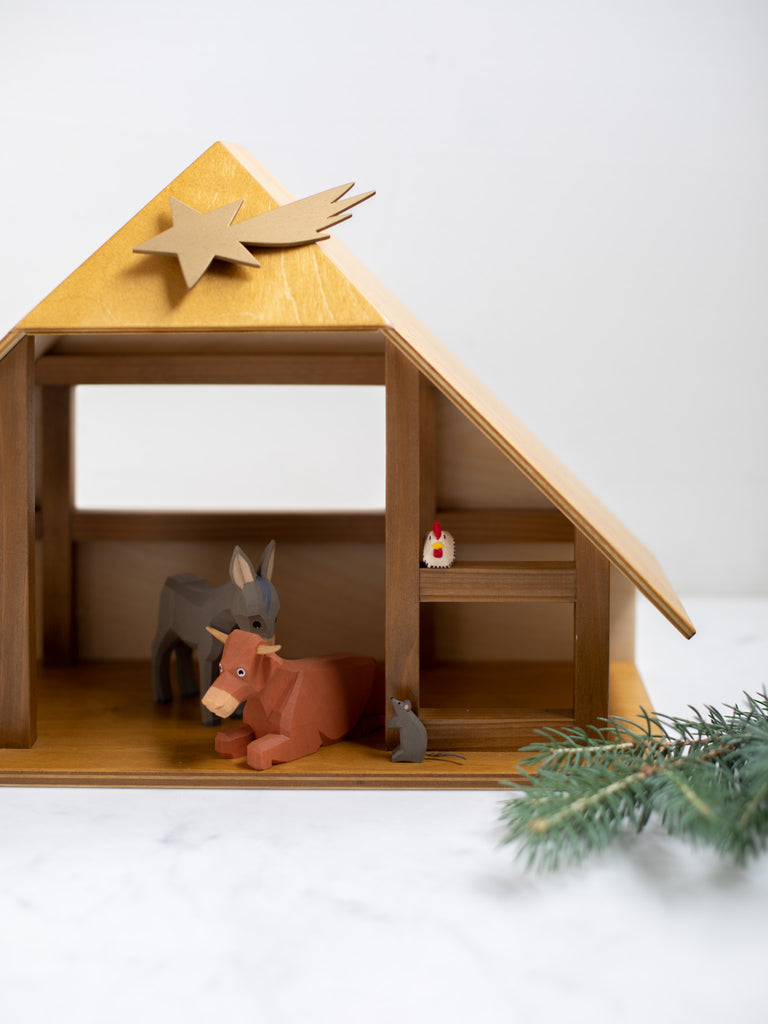 A large wooden and triangle shaped manger, with a few animals sitting inside of it.