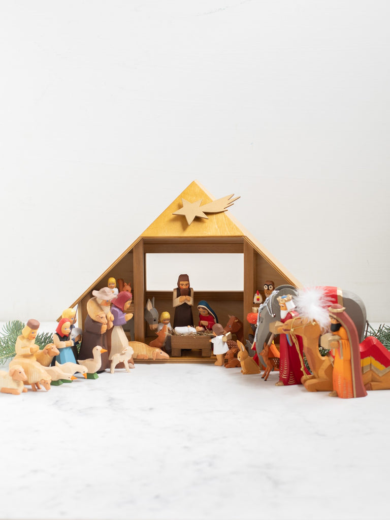 A nativity scene with all included characters under and around a manger.