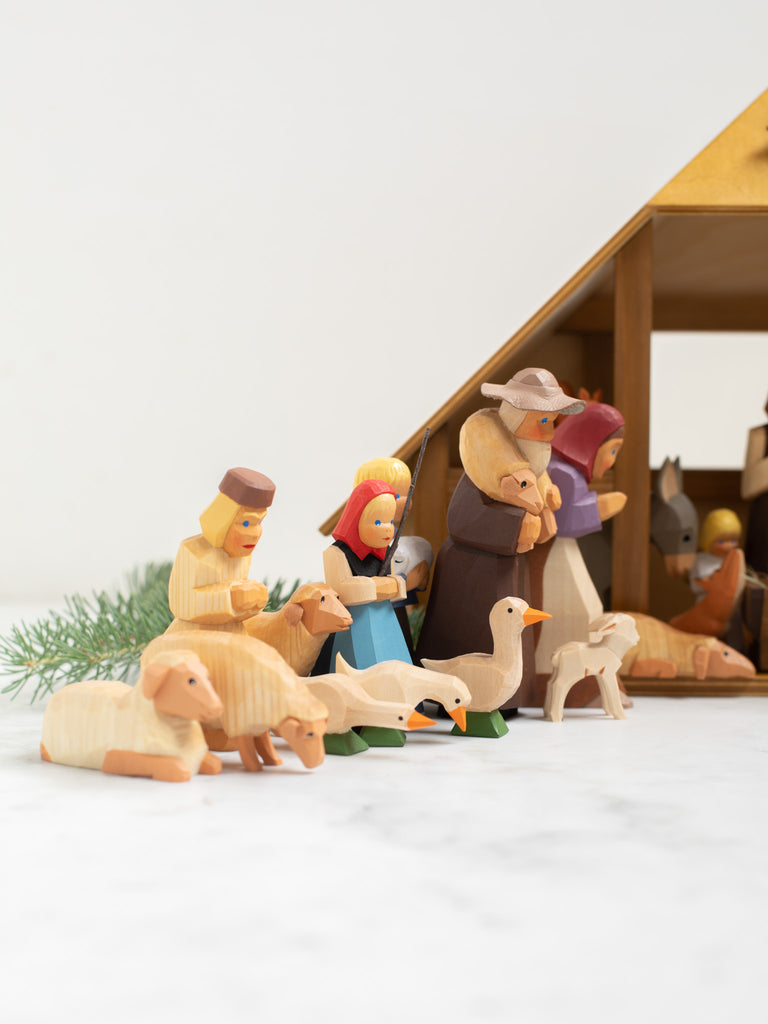 Multiple wooden human and animal figures kneeling and bowing.