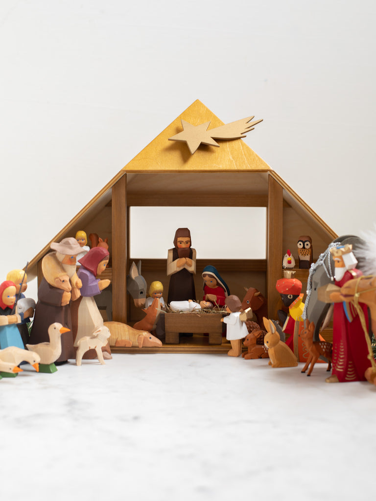 A nativity scene with all included characters under and around a manger.