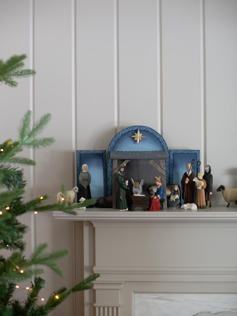 The entirety of the nativity characters positioned in front of a large blue and brown manger background.