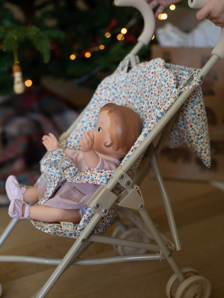 A child pushes one of the baby dolls with pink clothing in a dotted fabric stroller.