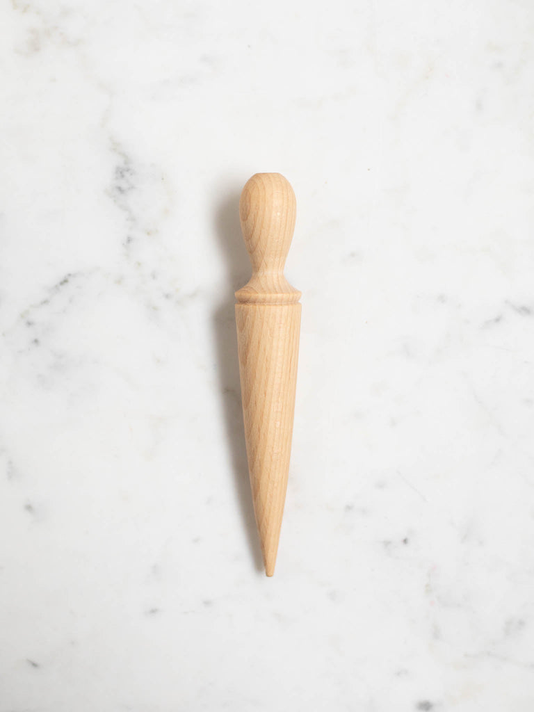 A light wood pointed seed dibbler with a rounded handle.