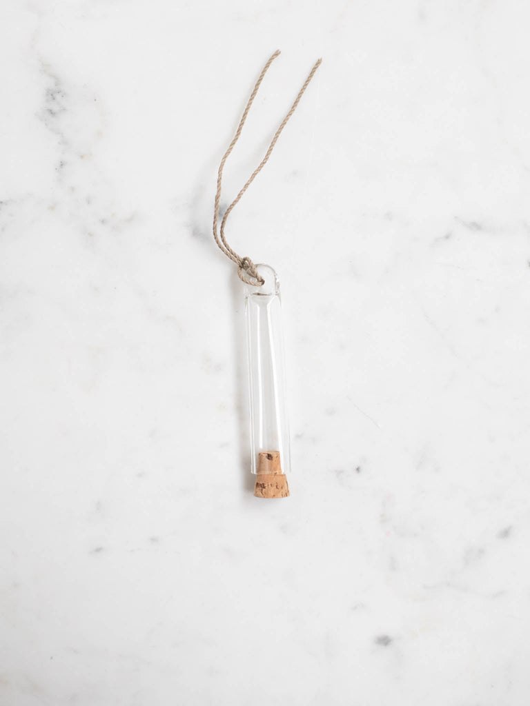 Small and short glass capsule with a cork top.