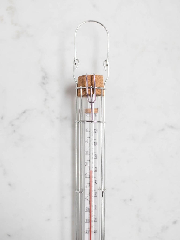 A close up of the cork screw top and metal handle of the glass thermometer.
