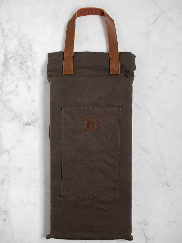 The canvas dark brown log carrier bag folded into a vertical rectangle shape for condensed storage.
