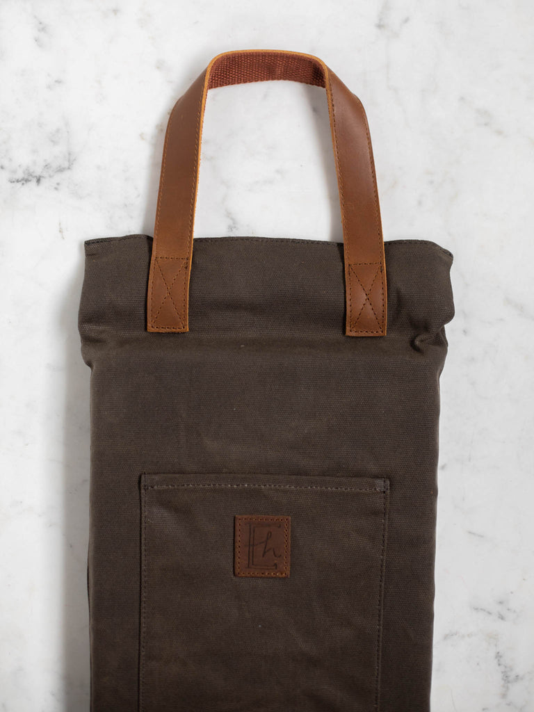 The canvas dark brown log carrier bag folded into a vertical rectangle shape for condensed storage.
