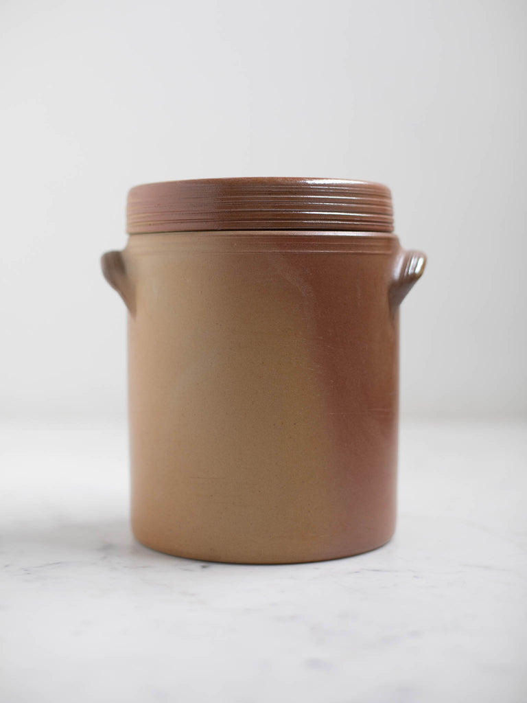 Brown condiment jar with a lid and two built in handles. 