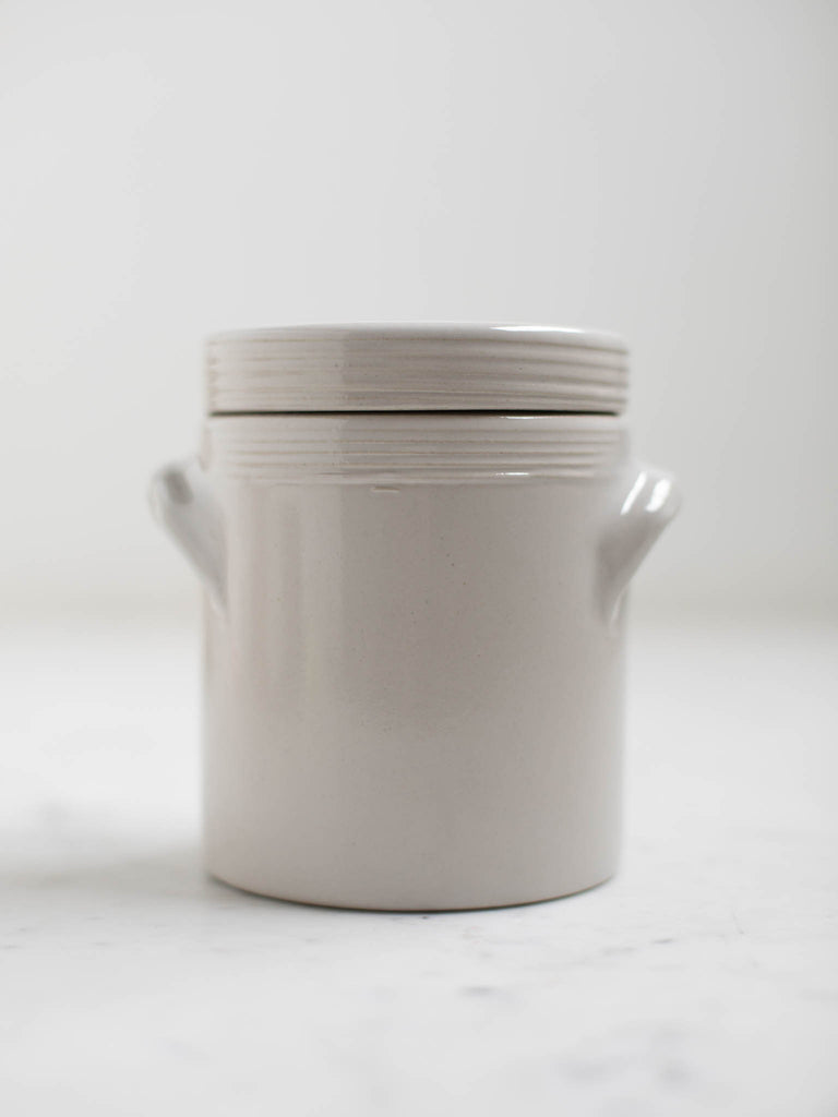 White condiment jar with two built in handles and a lid. 