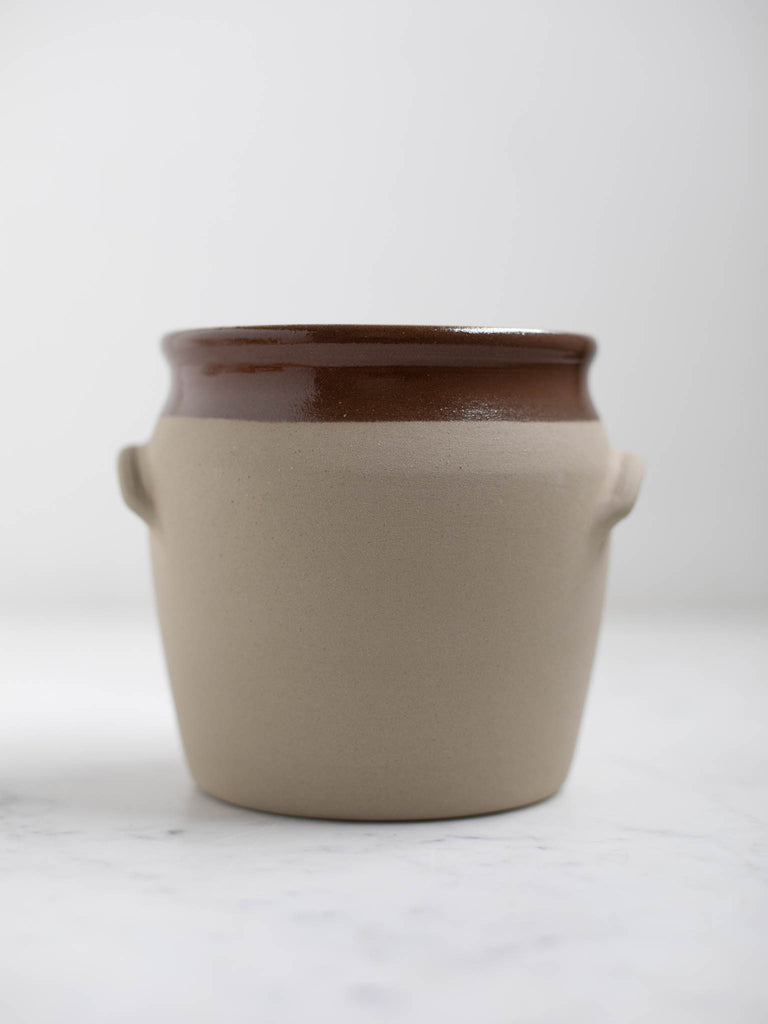 White barrel crock with a brown rim and built in handles. 